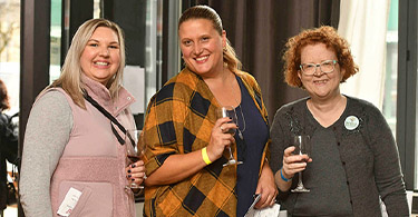 3 women posing with wine